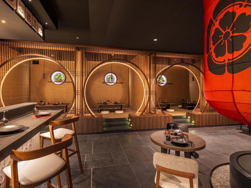 Nowoczesna japońska restauracja z okrągłymi miejscami do siedzenia, drewnianymi meblami i czerwoną latarnią.