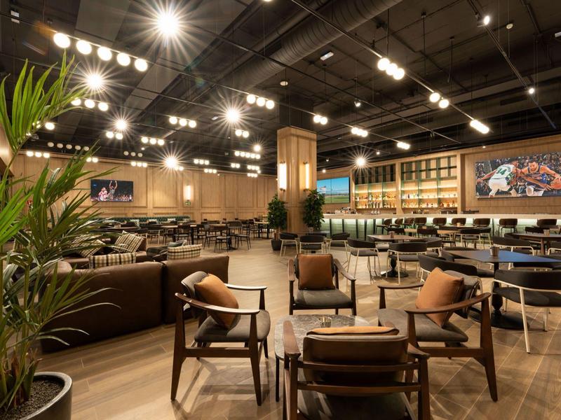 Przestronna, przytulna strefa wypoczynkowa hotelu z miejscami do siedzenia, roślinami i nowoczesnym oświetleniem.