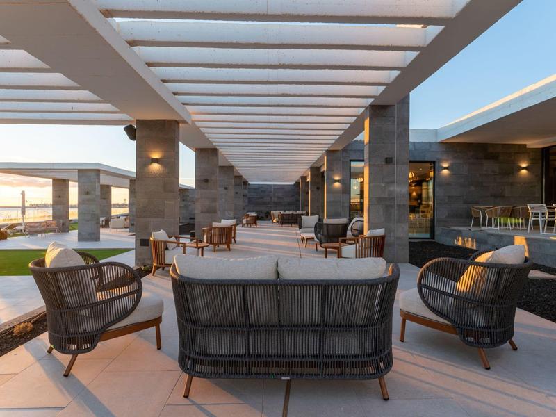 Otwarta przestrzeń lounge z nowoczesnymi meblami i oświetleniem na tarasie hotelowym.