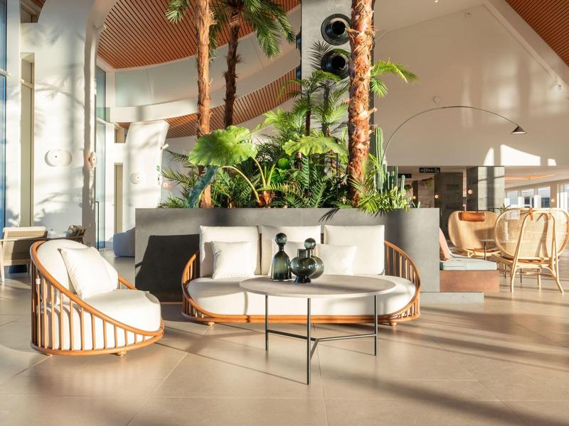 Jasne, przytulne wnętrze lounge z białymi fotelami i nowoczesnymi roślinami w hotelu