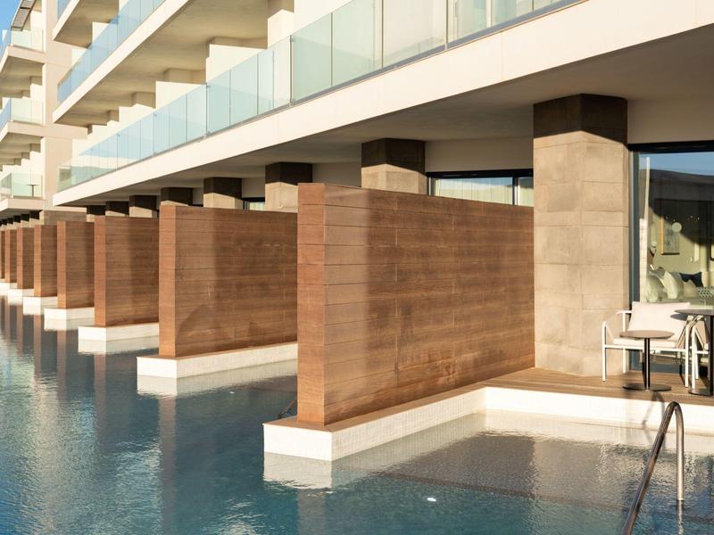 Nowoczesne pokoje hotelowe z prywatnymi tarasami i basenami w minimalistycznej architekturze.