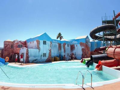 Grande parco scivoli acquatici con più scivoli e una piscina poco profonda sotto un cielo blu.