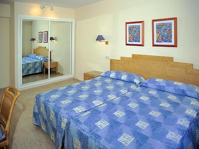 Camera d'hotel accogliente con letto grande, copriletto blu e armadio con specchio.