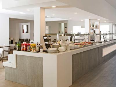 Modernes Restaurant mit großem Buffet, weißen Wänden, grauem Boden und minimalistischen Möbeln.