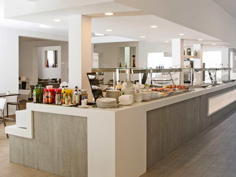 Modernes Restaurant mit großem Buffet, weißen Wänden, grauem Boden und minimalistischen Möbeln.