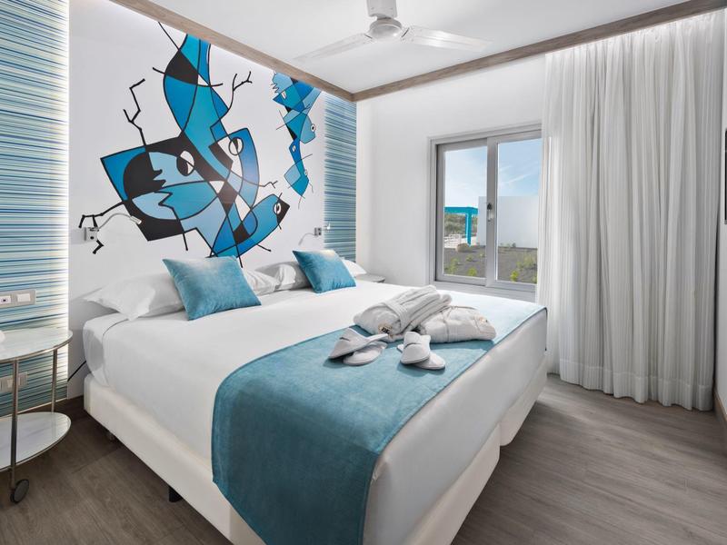 Camera d'hotel moderna con letto matrimoniale, arte astratta e grande finestra con vista.