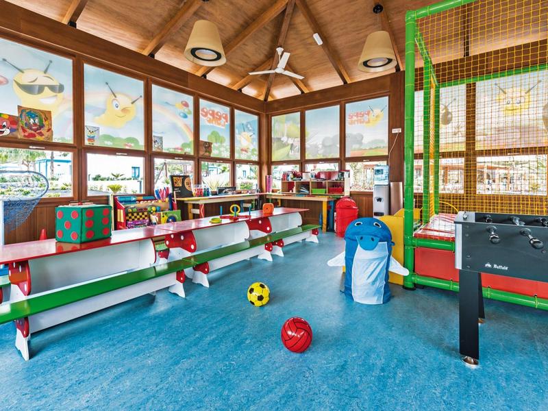 Sala giochi colorata per bambini con giochi a torre, porta da calcio e attrezzature per i più piccoli.
