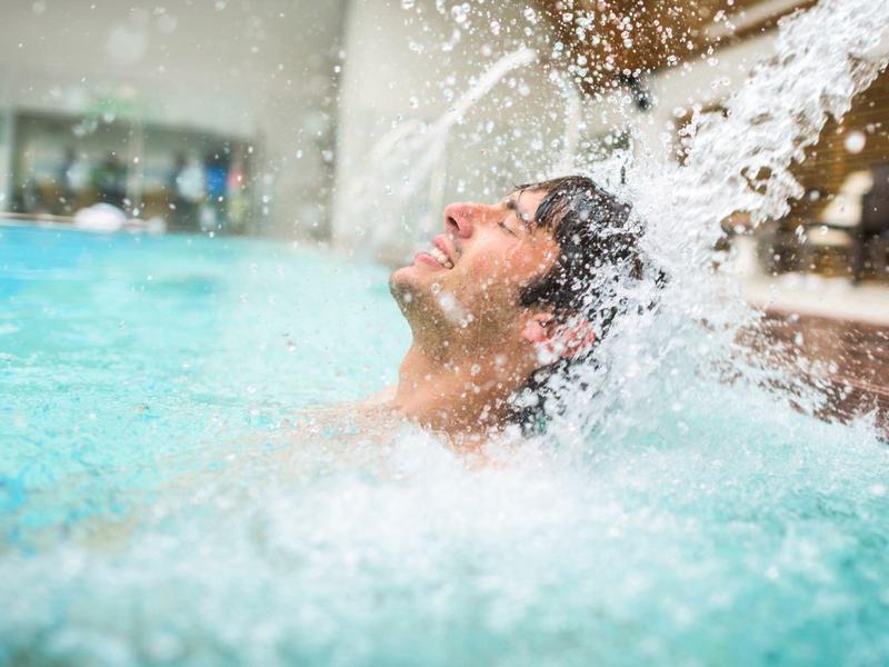 Area giochi acquatica per bambini con scivoli colorati in piscina sotto il sole.