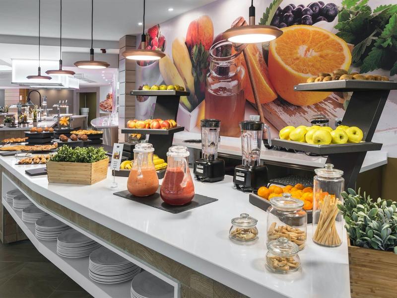 Buffet con frutta fresca, succhi e ingredienti per la colazione in un ristorante d'hotel luminoso.