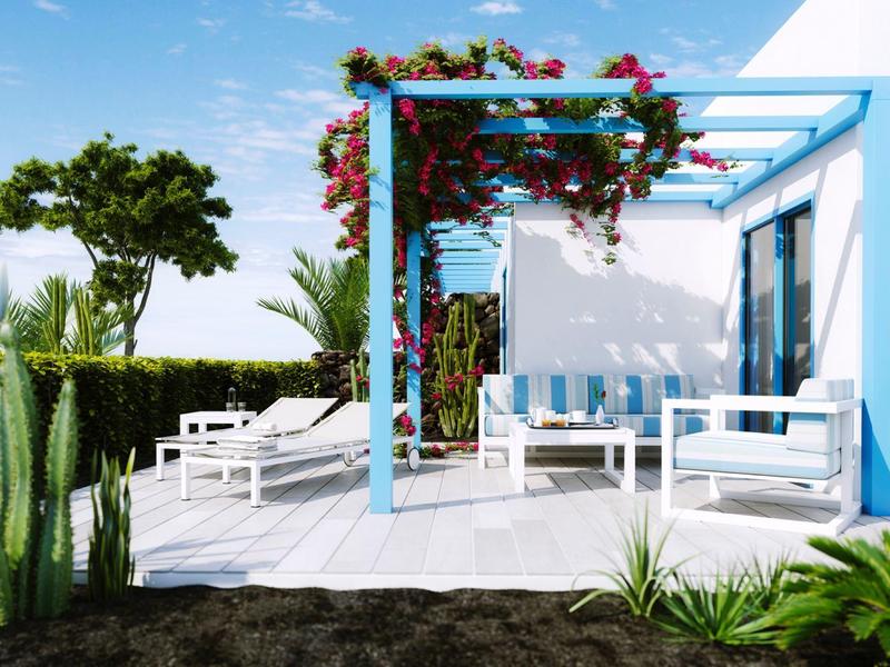 Area esterna moderna con pergola azzurra, mobili bianchi e vegetazione rigogliosa.