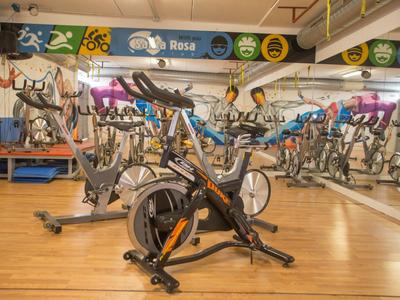 Innenaufnahme eines Fitnessraums mit mehreren Spinning-Fahrrädern auf einem Holzboden