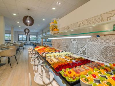 Modernes Hotelrestaurant mit langem Buffet voller bunter Obst- und Gemüsesorten.