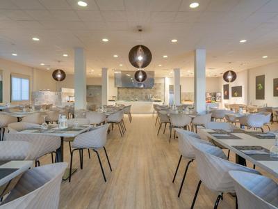 Modernes Restaurant mit grauen Stühlen, Holzboden und runden Lampen an der Decke.