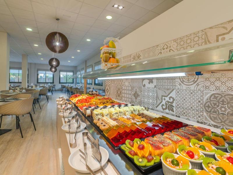 Buntes Buffet mit Früchten und Desserts in modern eingerichteter, heller Restaurantumgebung.