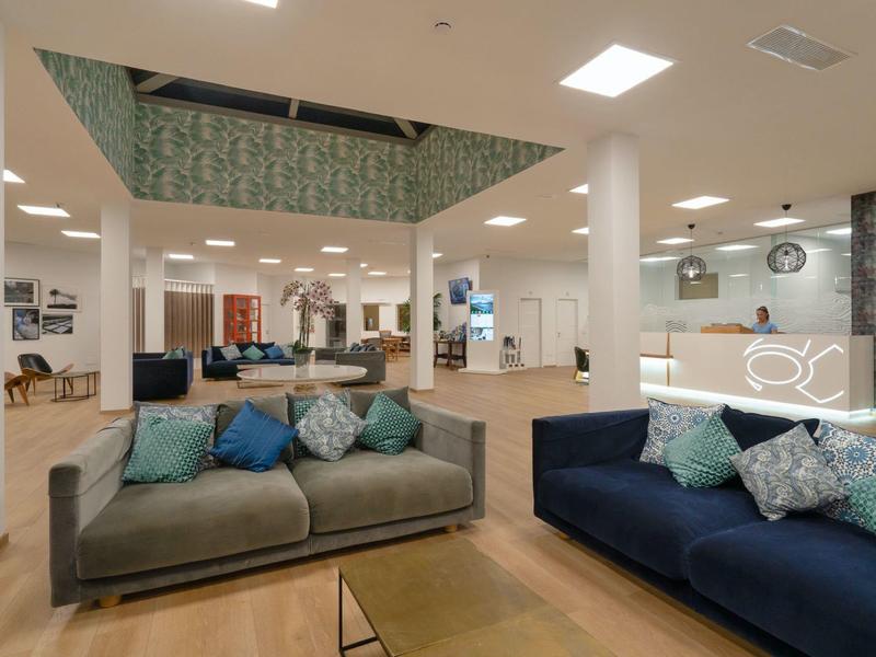 Großer moderner Raum mit zwei Sofas, bunten Kissen, Holzfußboden und weißen Säulen.