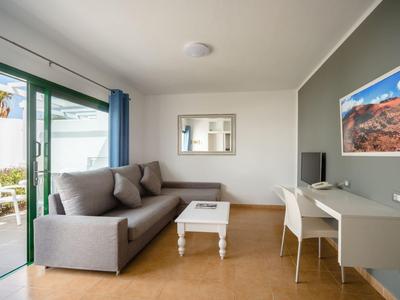 Modern living room with gray sofa, white table, and workspace next to a terrace.