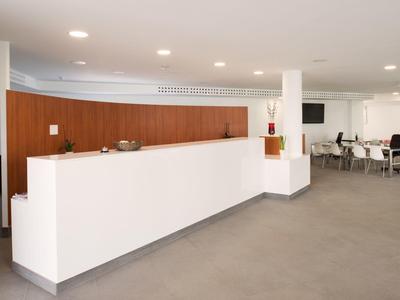 Moderner Empfangsbereich mit langem weißen Tresen und Holzverkleidung, hell und minimalistisch gestaltet.