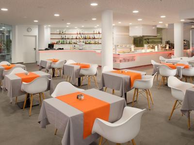 Bright hotel bar with tables, white chairs, and orange table runners in a modern design.