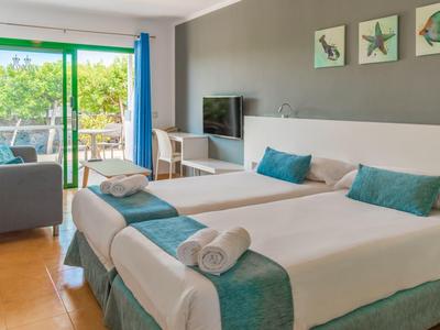 Camera d'hotel moderna con due letti singoli, terrazza e vista mare.