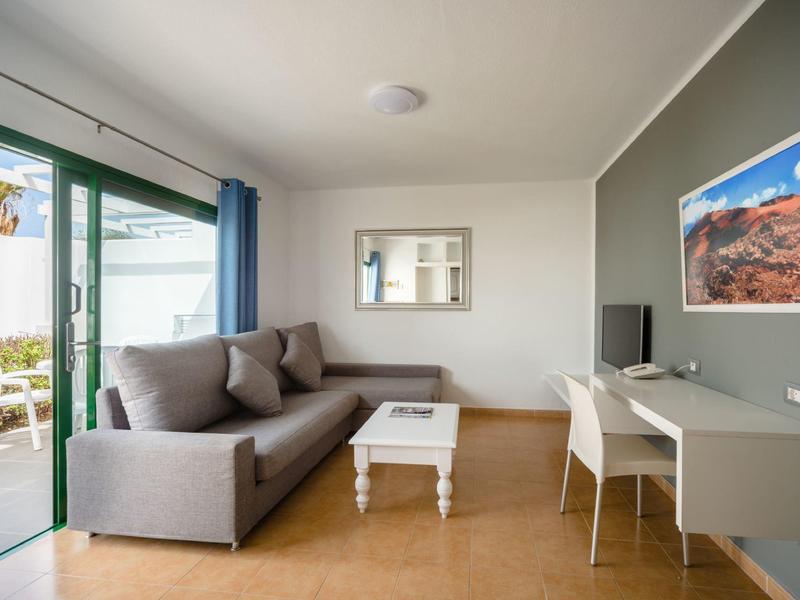 Soggiorno moderno con divano grigio, piccolo tavolo bianco, scrivania e vista sulla terrazza.