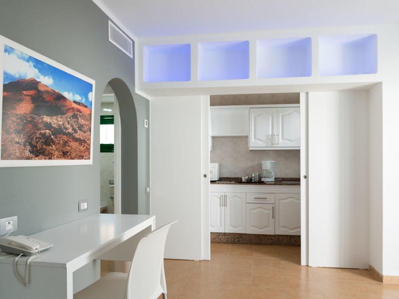 Angolo cottura luminoso in una camera d'hotel moderna con tavolo e sedia bianchi.