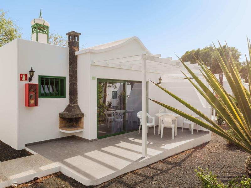 Casa vacanze moderna con terrazza, stufa e sedie da giardino bianche sotto un ombrellone