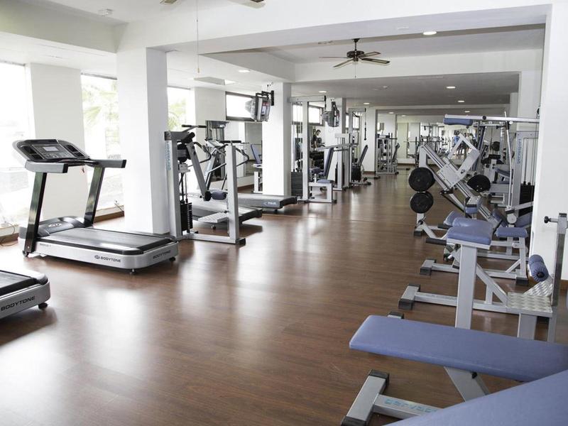 Großer, heller Fitnessraum mit Holzfußboden und verschiedenen Trainingsgeräten und Laufbändern.