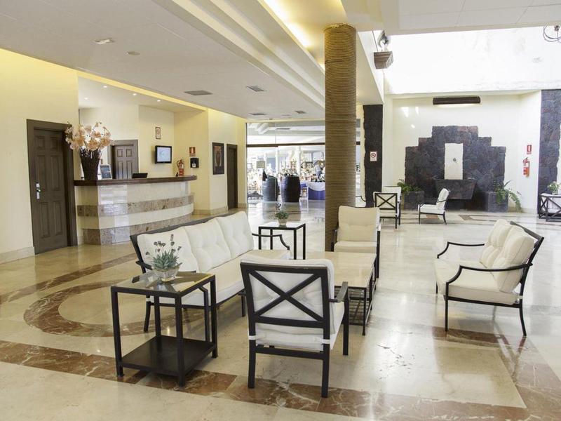 Großer heller Empfangsbereich mit Sesseln, Tischen und Marmorboden in hellem Beige und Braun.