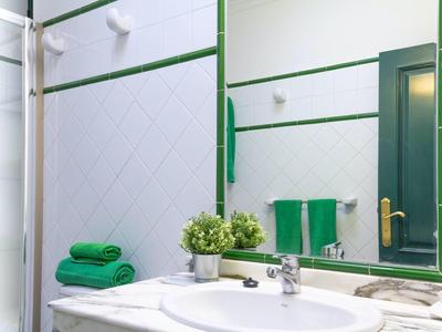 Bagno luminoso con pareti bianche, cornice dello specchio verde e asciugamani freschi.