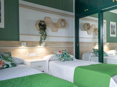 Due letti singoli con coperte verdi in una moderna camera d'hotel verde con uno specchio