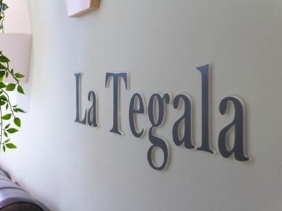 Parete con scritta elegante 'La Tegala' e pianta sul lato