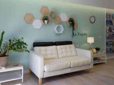 Sala d'attesa accogliente con divano bianco, piante verdi ed elementi decorativi a parete