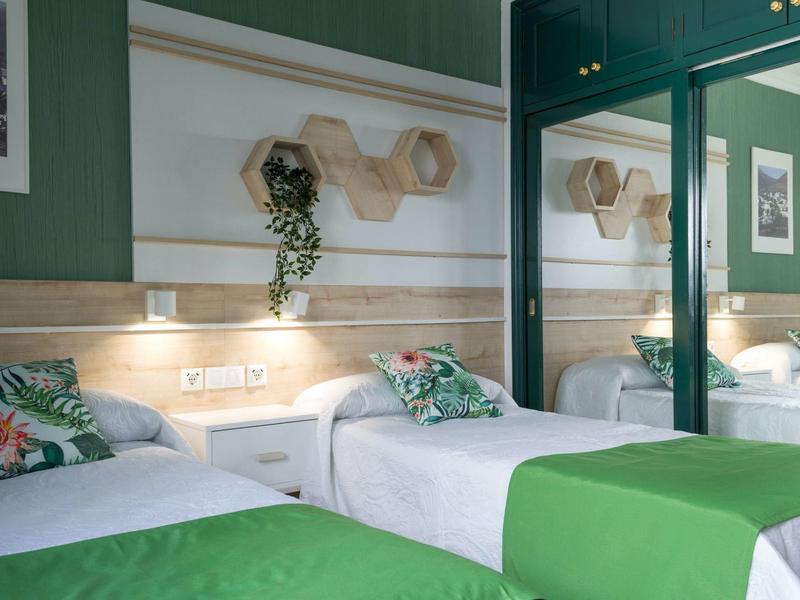 Due letti singoli con coperte verdi in una moderna camera d'hotel verde con uno specchio