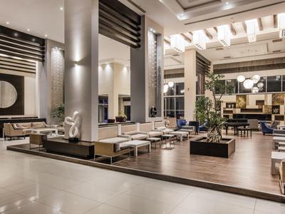 Ruime en moderne hotellobby met elegante zithoeken en verfijnde verlichting.