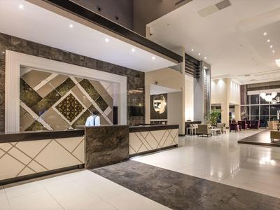 Moderne hotel lobby met receptie, grote spiegels en stijlvolle verlichting.