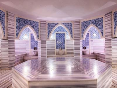 Interieur van een luxe Turks hammam met marmeren bassin en decoratieve tegels.