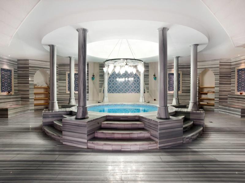 Elegante ronde zwembad in een lichte wellnessruimte met zuilen en een ontspannende sfeer.