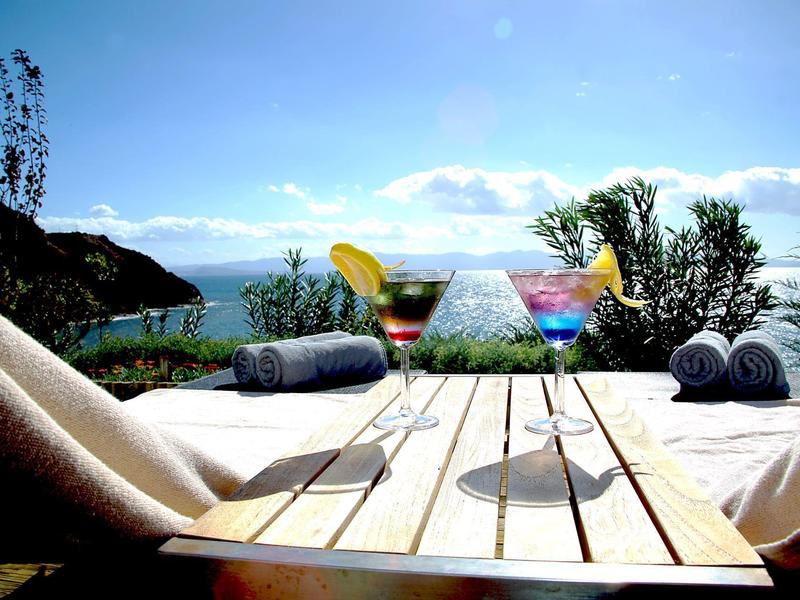 Ontspannend buitenterras met cocktails en zeezicht op een zonnige dag.