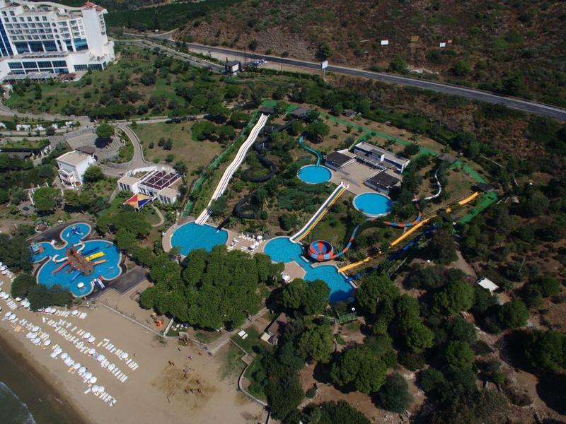 Luchtfoto van een resort met zwembaden, strandstoelen en aangrenzend strand.