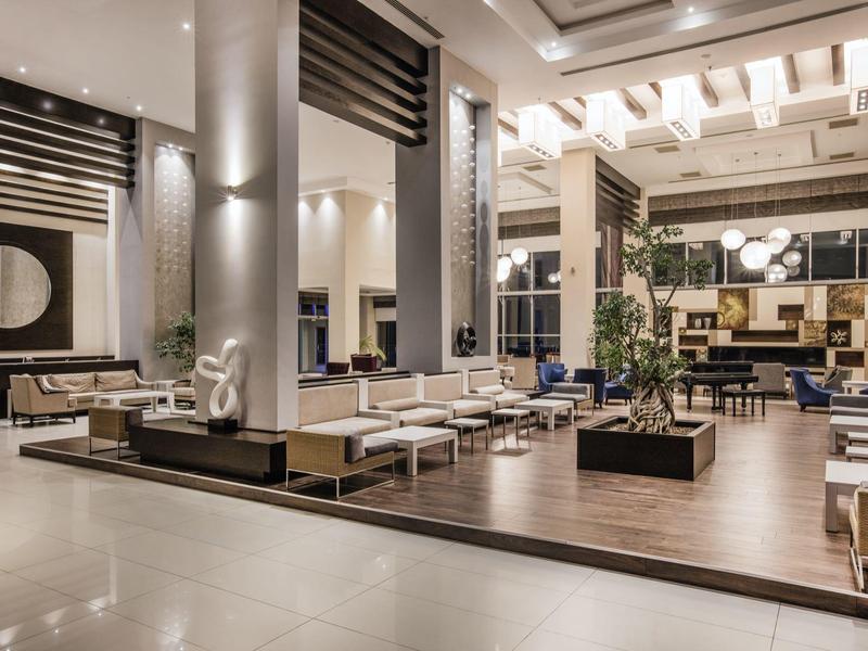 Ruime en moderne hotellobby met elegante zithoeken en verfijnde verlichting.