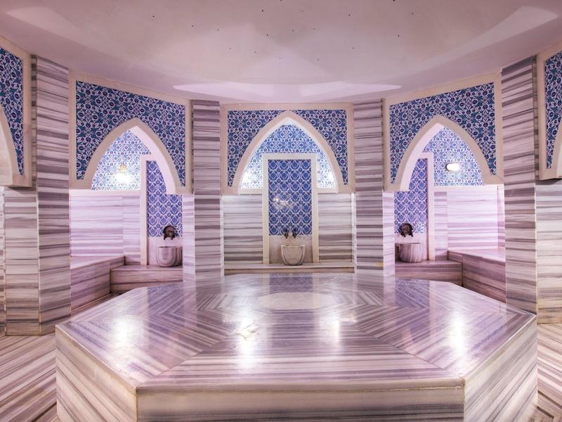 Interieur van een luxe Turks hammam met marmeren bassin en decoratieve tegels.
