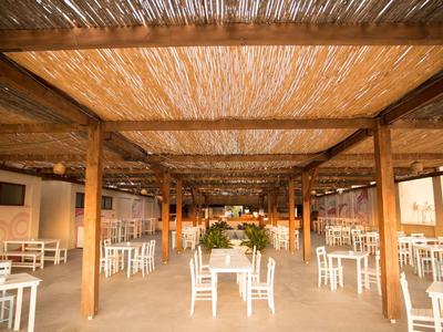 Grote open eetruimte met witte stoelen, houten balken en natuurlijk dak.