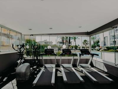 Moderne Fitnessstudio mit Laufbändern und Fahrrädern, großes Fenster mit Blick auf Außenbereich