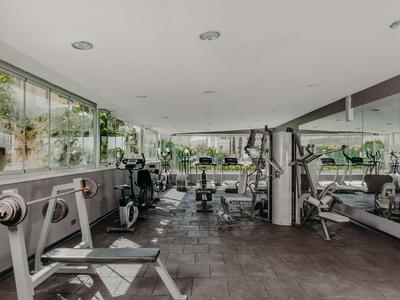 Moderner Fitnessraum mit zahlreichen Trainingsgeräten und großen Fenstern mit Blick ins Grüne.