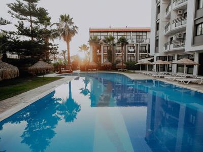 Een rustige hotelzwembad bij zonsondergang met palmbomen en ligstoelen.