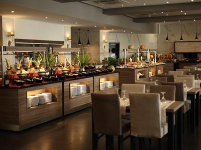 Modern hotelrestaurant buffet met tafels en diverse gerechten.