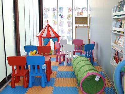 Kleurrijke speelruimte voor kinderen met kleine stoelen, tafel, tent en tunnel in een kamer.