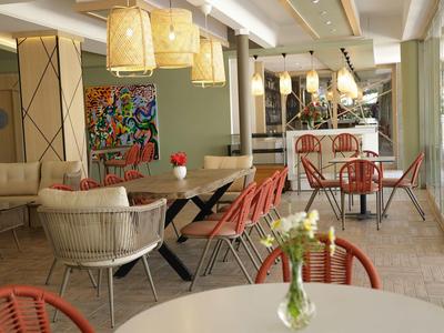 Helles Café mit Mix aus modernen und klassischen Möbeln, Blumen auf den Tischen, große Fenster