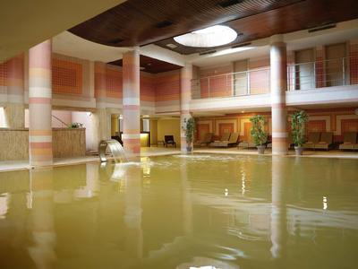 Groot binnenzwembad met zuilen en decoratieve muurschilderingen in een stijlvolle spa.