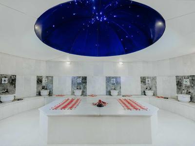 Ronde moderne lounge met witte inrichting en een plafond met sterrenhemel.